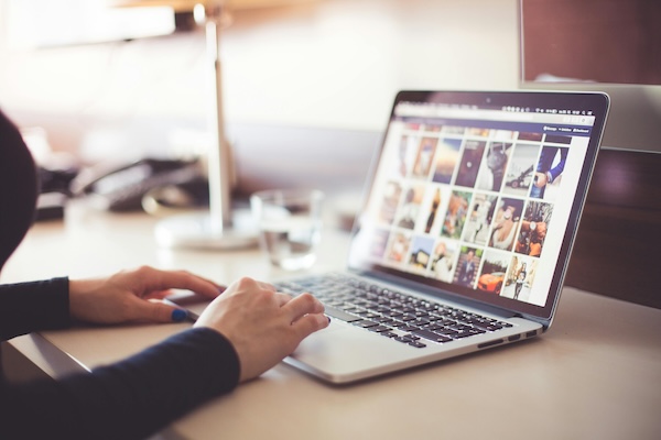 Fotos für Webseiten: Eine Person sitzt am Laptop und schaut sich eine Bilddatenbank wie Adobe Stock, Shutterstock oder iStock an.