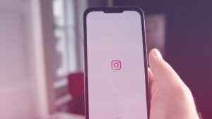 Content-Formate auf Instagram: Eine PErson hält ein Handy in der Hand auf dem das Instagram-Logo zu sehen ist.