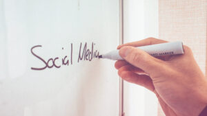 Social Media Strategie: Eine Person schreibt das Wort Social Media auf ein Whiteboard.