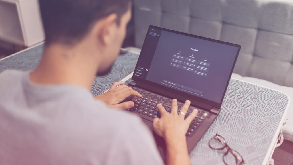 GEO statt SEO: Ein junger Mann sitzt am Laptop an ChatGPT.